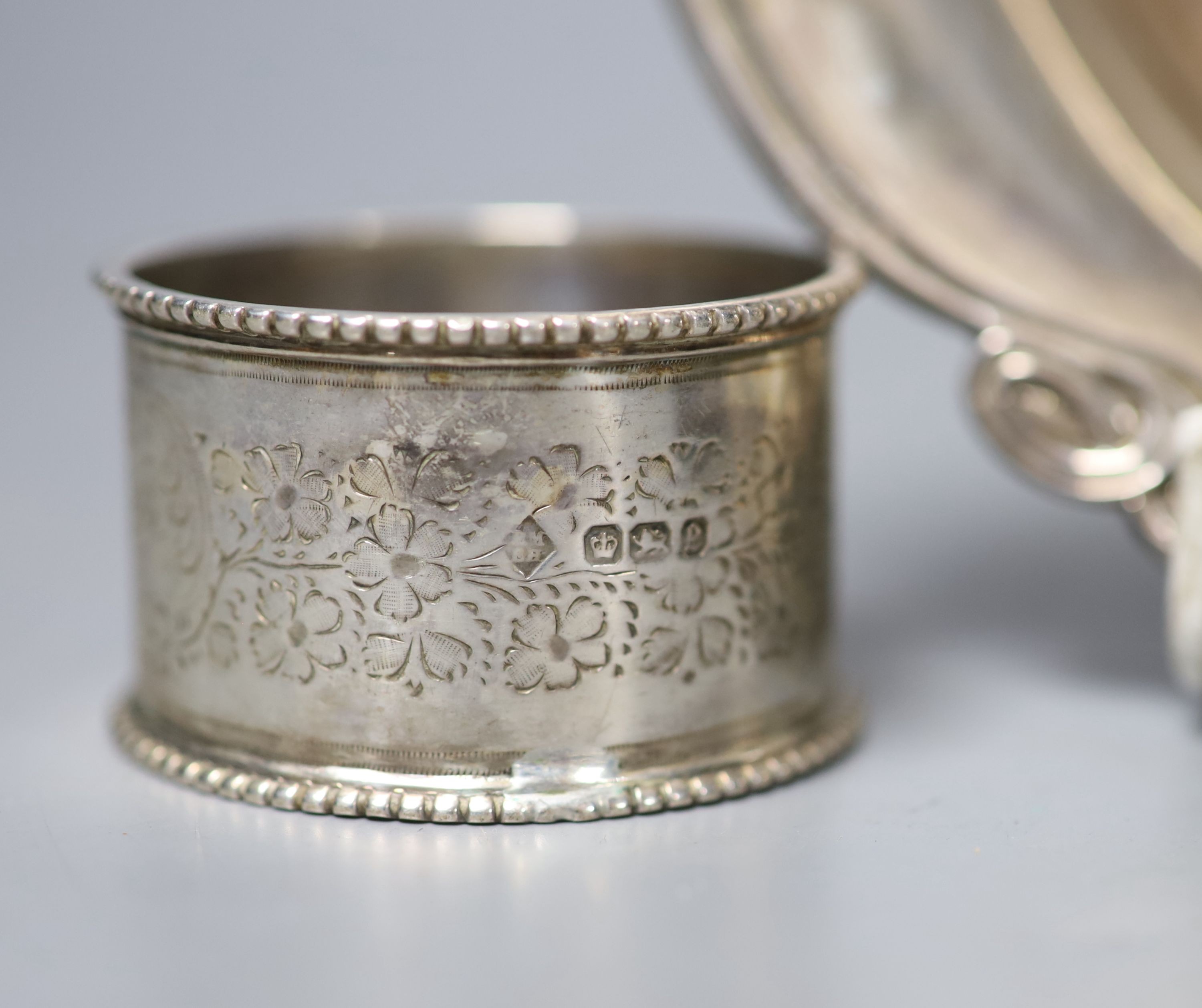 A George V Art Nouveau silver spoon, D & M Davis, Birmingham, 1911, 18.2cm, together with a modern silver mounted wine coaster and a silver napkin ring.